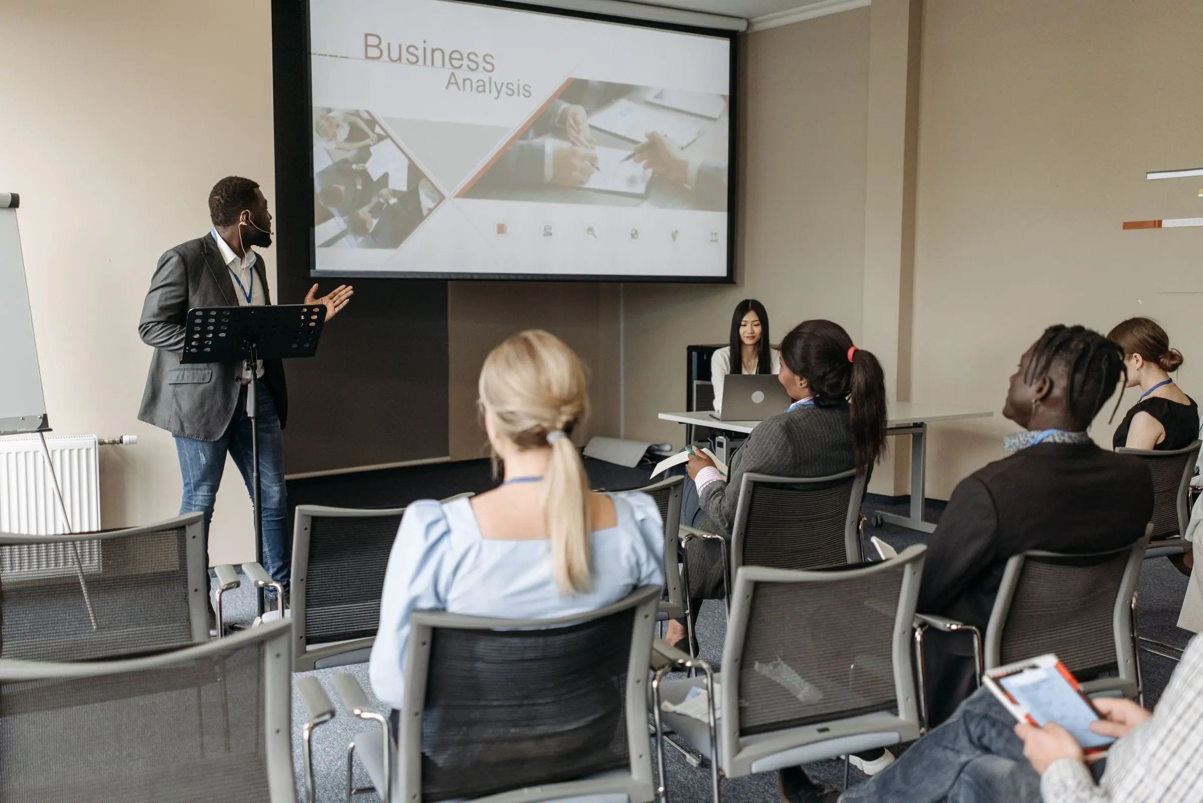 A trainer presenting to seated participants in a conference room